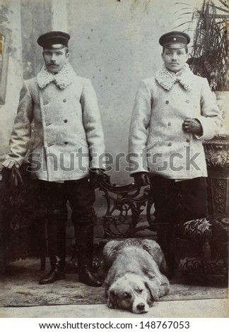RUSSIAN EMPIRE - CIRCA 1910:Vintage photo shows two young men railroad workers and dog. Railroad workers. Nostalgic picture. Circa 1910. Russian Empire, beginning of 20th century.