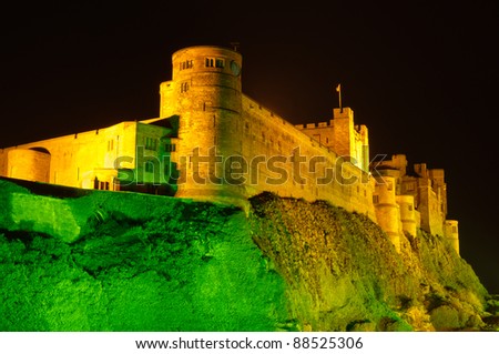 Bamburgh Castle at night close up / Bamburgh Castle at night illuminated by green and golden lights