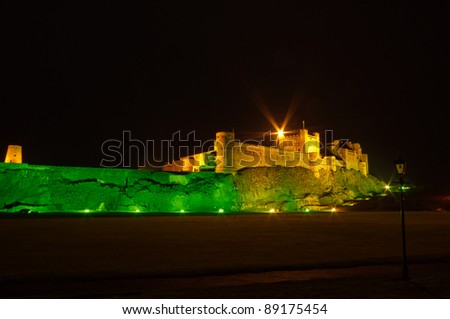 Bamburgh Castle at night with lamp post / Bamburgh Castle at night illuminated by green and golden lights