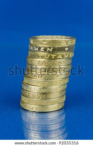 Pile of coins isolated on blue background with reflection / Stack of pound coins