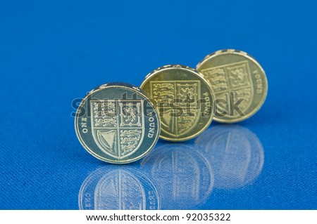 Row of coins with reflection isolated on blue background / Three pound coins