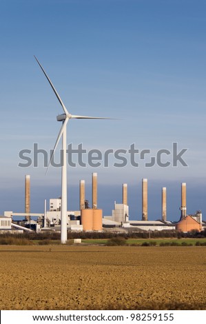 Modern wind turbine with old factory behind it vertical