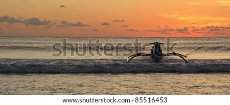 Traditional boat coming back to the beach during sunset