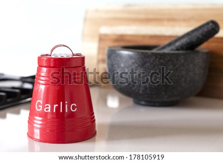 Red garlic storage container on kitchen bench