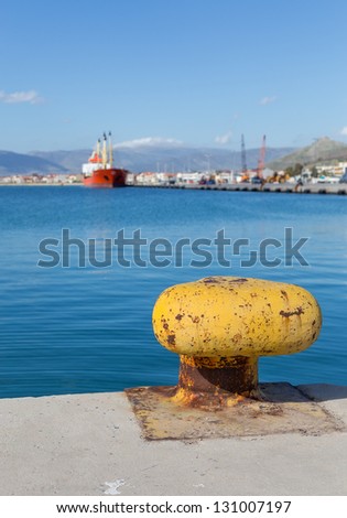 Yellow rusty bollard with sea and ship background