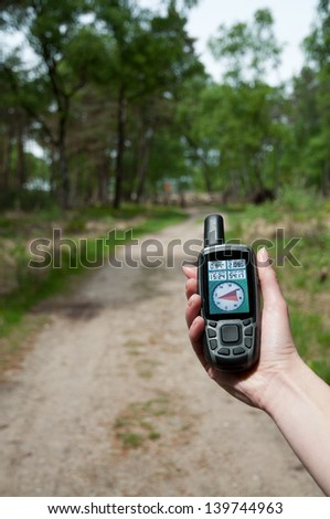 a woman hand hold a GPS device to secure the route through the forest