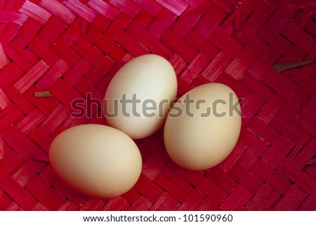 Three big ecological chicken eggs in red wicker basket.