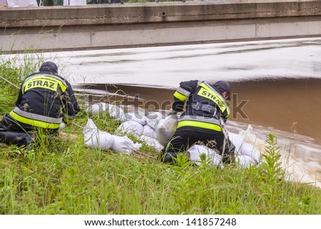 ZIELONA, POLAND - JUNE 11:Man from fire brigade make sandbank from sand bags on june 11, 2013 in Kalety. High water level on Zielona lake and Mala Panew river.