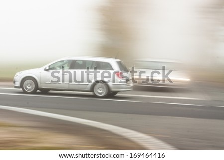 Moving cars on foggy weather in country road in Poland.