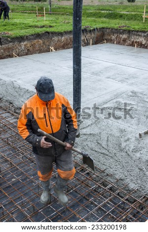 Worker pouring concrete mix into reinforced structure at the building site.