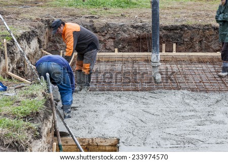 Workers pouring concrete mix into reinforced structure at the building site.