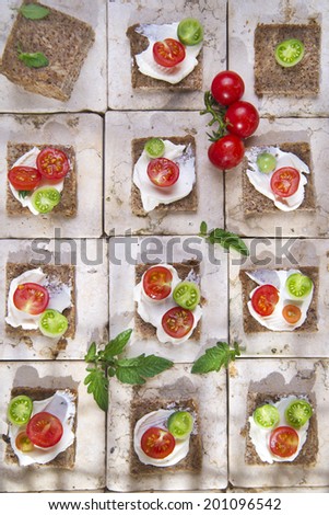 Presentation of slices of wholemeal bread with cheese and cherry tomatoes