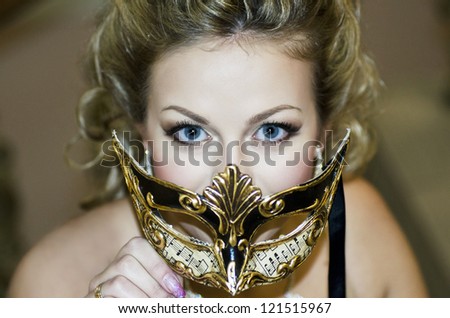 alluring blue-eyed blonde woman holding a mask. attractive blonde covers a face with mask decorated with notes