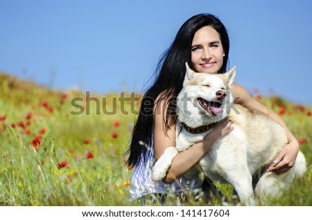 Beautiful woman with husky outdoors.Happy brunette woman with smiling siberian husky dog, sitting in a poppy field on a sunny day, on a walk with dog