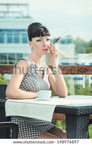 vintage beautiful woman in restaurant cafe with cigarette holder and coffee.Breakfast time.Stylish rich slim girl in retro dress.glamorous lady at vacation. Retro style.Audrey Hepburn style.series