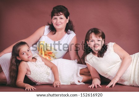 happy mother with daughter and granddaughter. smiling family. Two beautiful women and lovely little girl  in trendy wear posing in studio on brown background. family portrait