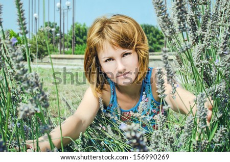 Beautiful young girl in green summer park. happy redhead woman posing outdoors in bushes of lavender. Romantic lady at vacation holidays