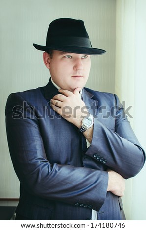 Gangster look. Handsome man with hat wearing dark suit. Retro fashion fifties young businessman.