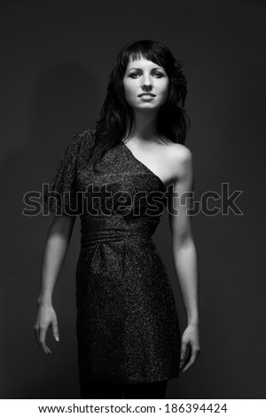 Beautiful fashionable woman in studio. Fashion portrait of young sexy alluring woman girl in elegant evening dress posing on black background