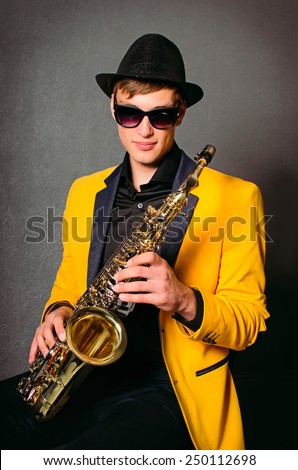 Handsome musician saxophonist with saxophone. Young saxophone player in studio. Jazz-band