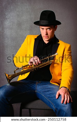 Handsome musician trumpet player with trumpet at studio. Jazz-band. Brutal young musician holding trumpet