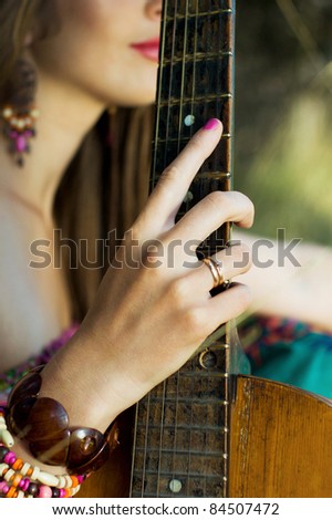 guitar and female hand close up. attractive young woman holding a guitar in hand. Outdoors