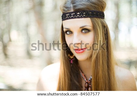 alluring young hippie woman outdoors. Beautiful long-haired hippie woman with nice makeup and hairstyle on the background of forest.Close-up portrait. happy hippie smiles