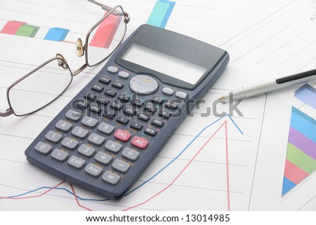 A bar graphs and calculator, pen, glasses on it.
