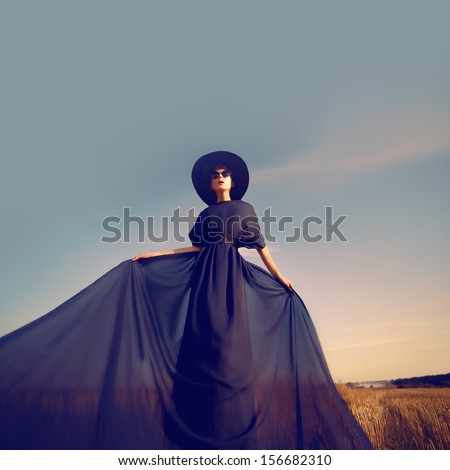 Fashion portrait of a girl in a black dress in the forest