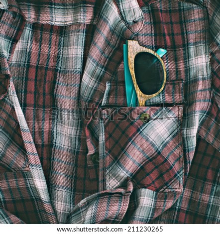 Wooden glasses in pocket of plaid shirt