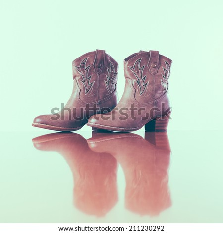 Vintage cowboy boots with reflection in wooden floor