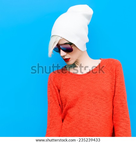 Fashion Blond Girl with trendy Cap and Sunglasses on a blue background