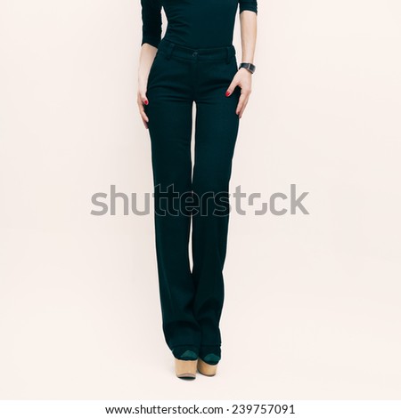 Fashion Lady in classic trousers and black blouse over white background.