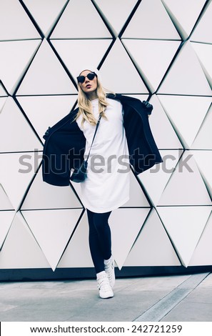 Glamorous Blonde standing at the wall. Urban fashion black and white  style