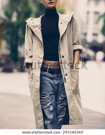 Girl on the street. Urban style. Cloak and ripped jeans.