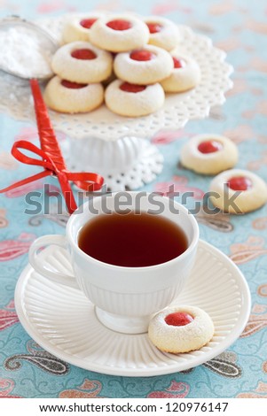 Cup of hot tea and homemade almond cookies filled with jam, selective focus