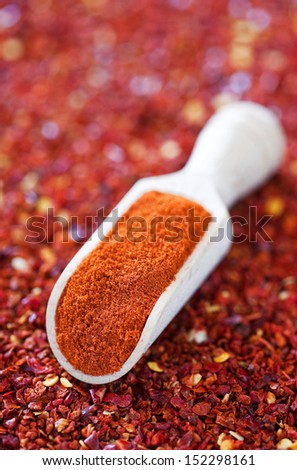 Red pepper flakes and ground paprika in wooden scoop, selective focus