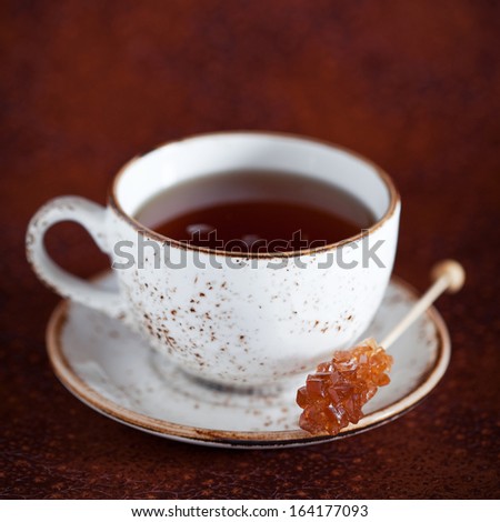 Cup of hot tea and rock candy sugar stick, selective focus