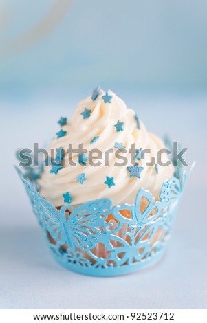 Cupcake with a swirl of vanilla butter cream frosting and blue decor, selective focus