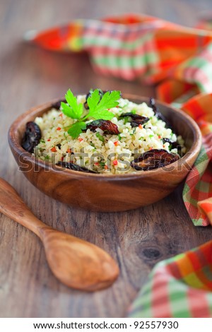 Bulgur, dried plum, chili, parsley salad in wooden bowl on the table, selective focus