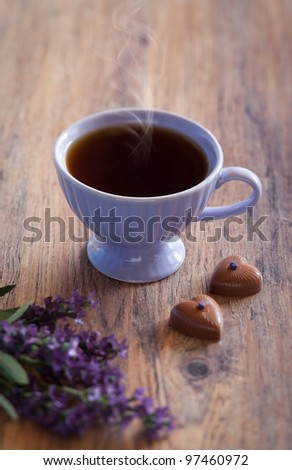 Cup of hot tea with lavender and chocolate candies with lavender, selective focus