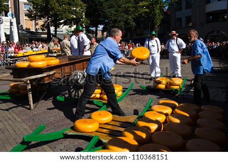 ALKMAAR, NETHERLANDS - AUGUST 10: Men charge cheese cart at the traditional cheese market on August 10, 2012 in Alkmaar, Netherlands. Every friday morning there is a typical cheese market at Alkmaar.