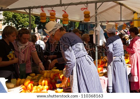 ALKMAAR, NETHERLANDS - AUGUST 10: People buy cheese in the open part of the cheese market on August 10, 2012 in Alkmaar, Netherlands. Every friday morning there is a typical cheese market at Alkmaar.