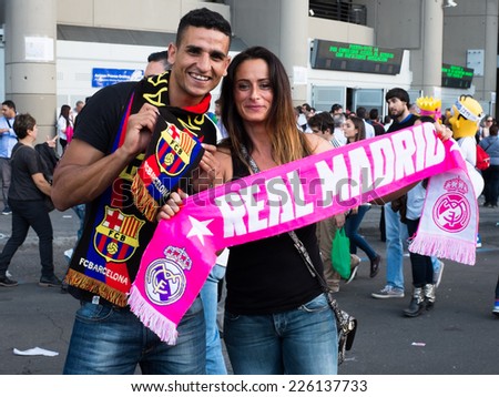 MADRID, SPAIN - OCTOBER 25, 2014: A young couple support Real Madrid and Barcelona FC soccer teams at the Real Madrid-Barcelona match.