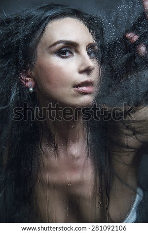 Young woman melancholy and sad at the window in the rain