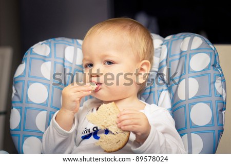 Baby in high chair eating bread