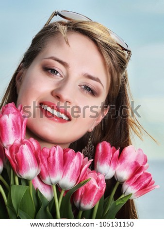 Beautiful young woman with pink tulips bunch of flowers