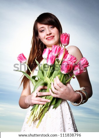 Beautiful young woman with pink tulips bunch of flowers