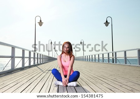 Attractive girl Young woman on pier Sits Crossed Legged Relaxing Old Wooden Pier