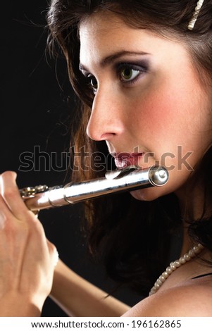 Art and artist. Young woman elegant girl flutist flautist musician perfomrer playing flute musical instrument on black. Classical music.